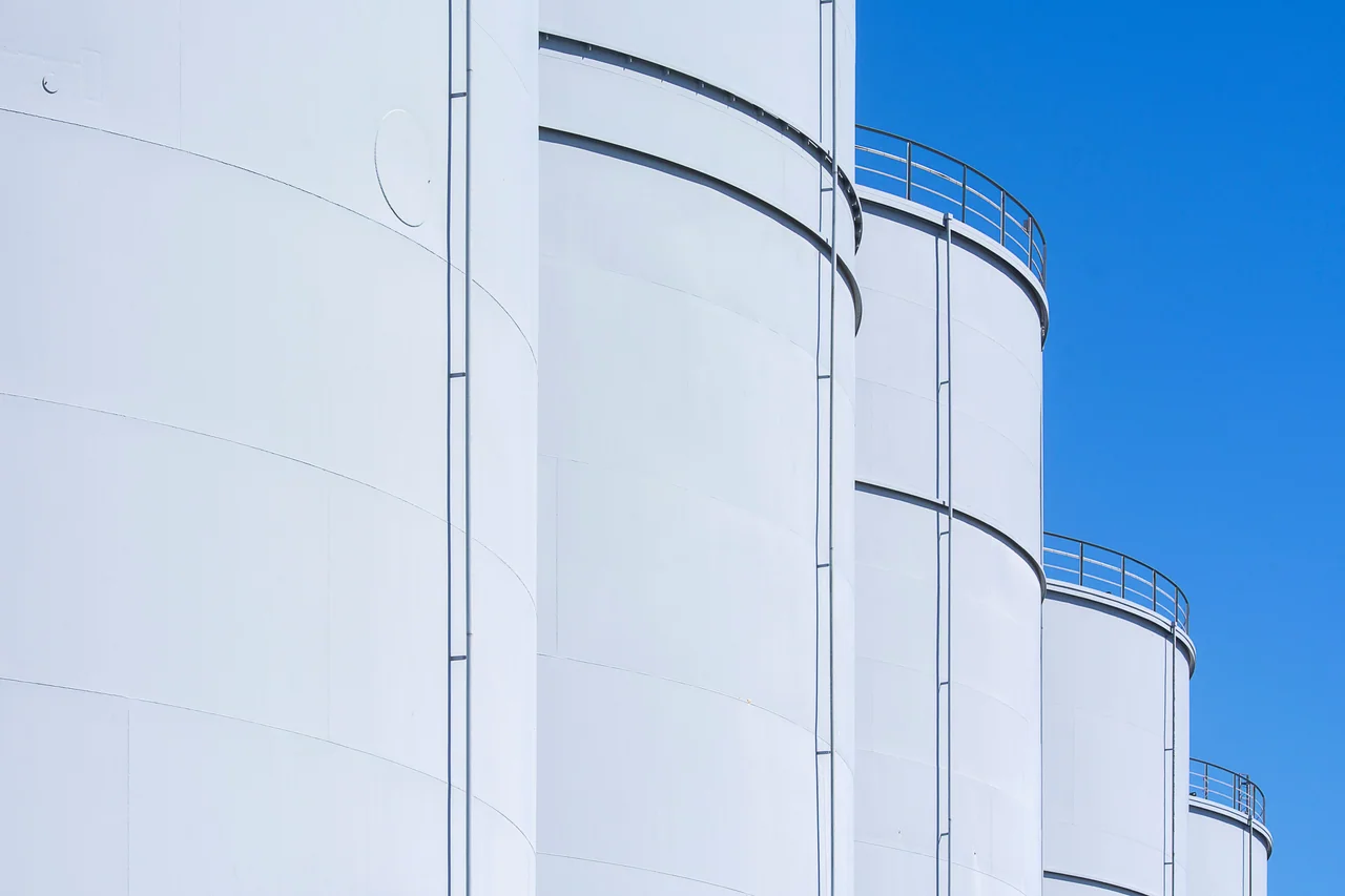White industrial storage tanks under a clear sky